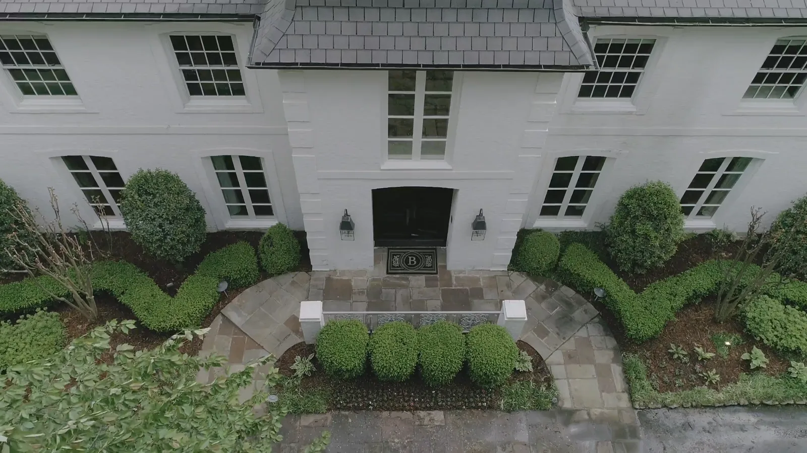 A home surrounded by mature trees, seen from a moving aerial perspective